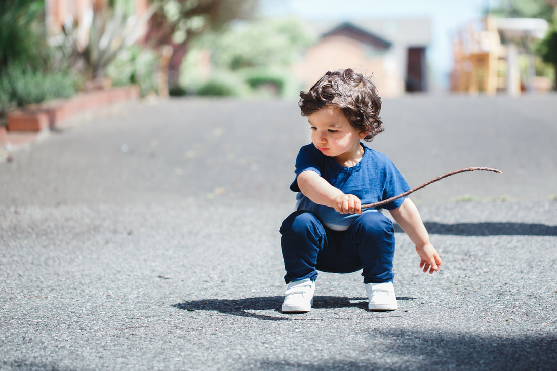 Picture of a toddler boy with a stick. Outdoor portrait photography, fun, lifestyle photo session at the park in Berkeley, California. 