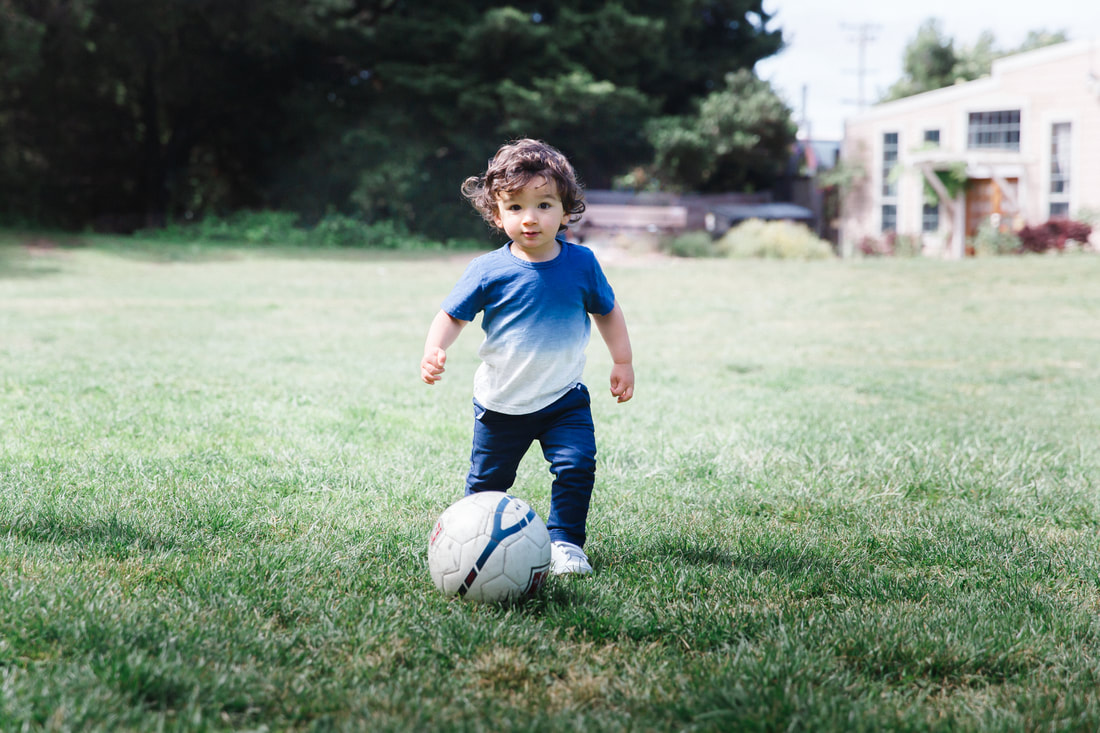 Picture of a toddler boy with soccer ball. Outdoor portrait photography, fun, lifestyle photo session at the park in Berkeley, California. 
