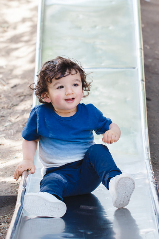 Picture of a Toddler boy sliding. Outdoor portrait photography, fun, lifestyle photo session at the park in Berkeley, California. 